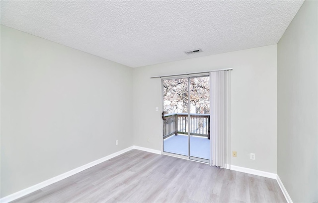 unfurnished room featuring baseboards, visible vents, a textured ceiling, and light wood finished floors