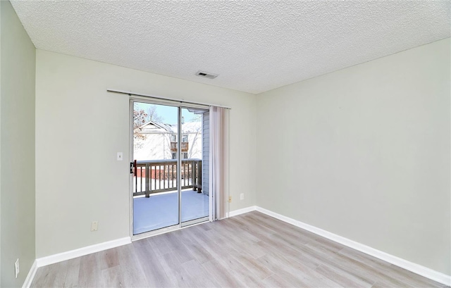 spare room with baseboards, visible vents, a textured ceiling, and light wood finished floors