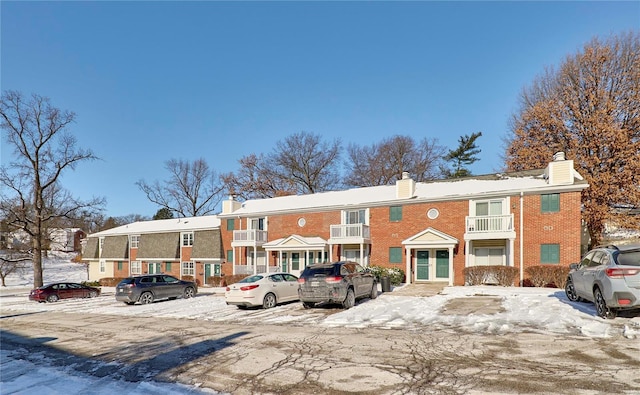 snow covered property featuring uncovered parking