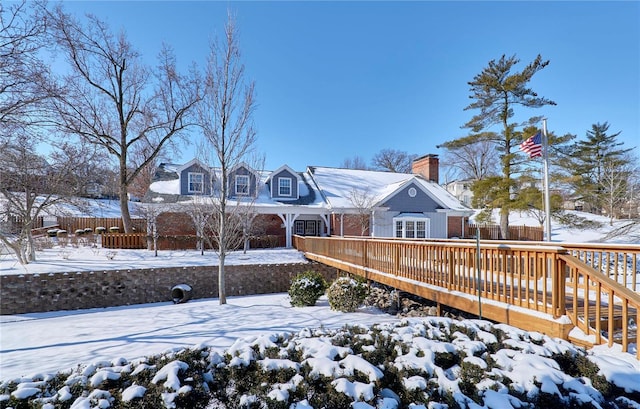 snow covered rear of property with a chimney and a deck