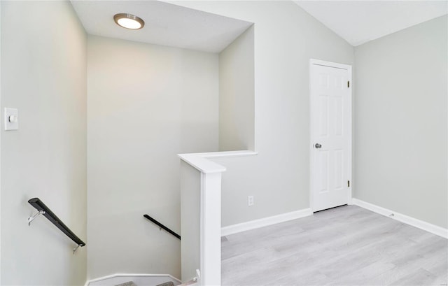 stairs with baseboards, wood finished floors, and vaulted ceiling