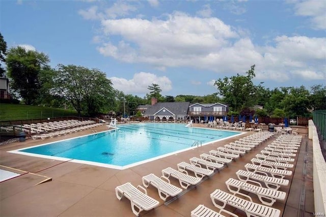 community pool with a patio and fence