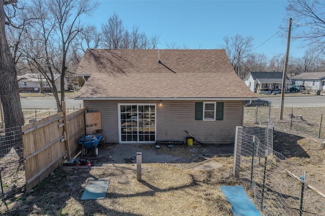 back of house featuring a shingled roof and fence