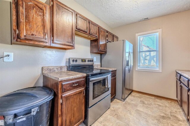 kitchen featuring baseboards, visible vents, stainless steel appliances, a textured ceiling, and light countertops