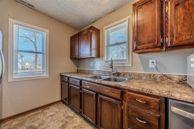 kitchen featuring a textured ceiling, a sink, visible vents, and baseboards