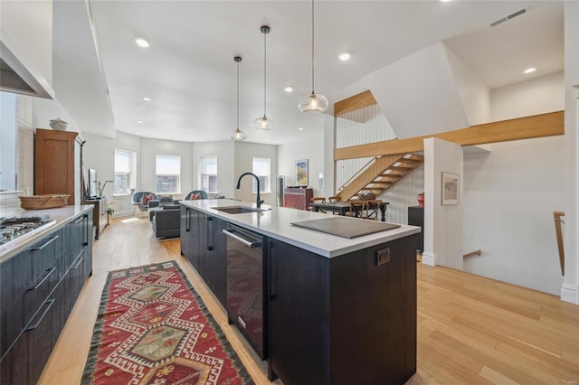 kitchen with modern cabinets, a sink, open floor plan, light wood-style floors, and light countertops