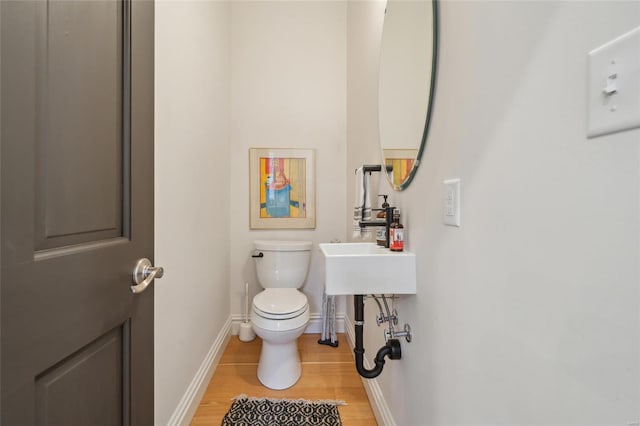 half bath featuring toilet, baseboards, and wood finished floors