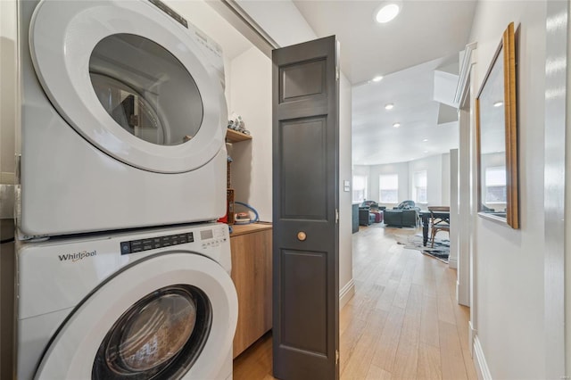 clothes washing area with laundry area, recessed lighting, stacked washer and clothes dryer, and light wood-style floors