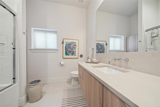 bathroom featuring toilet, tile patterned flooring, baseboards, bath / shower combo with glass door, and vanity