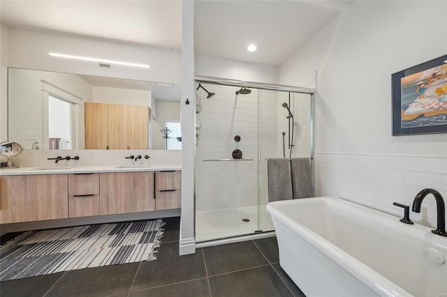 bathroom with a shower stall, double vanity, tile patterned floors, and a sink