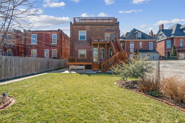 rear view of property with a lawn, a fenced backyard, a balcony, stairway, and brick siding