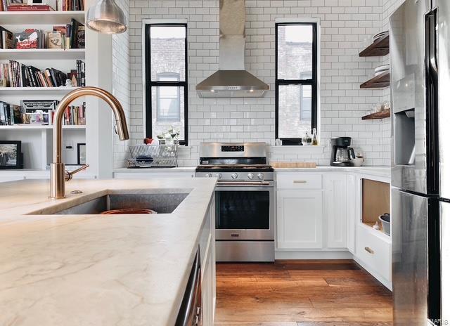 kitchen with stainless steel appliances, a sink, white cabinetry, wall chimney range hood, and open shelves