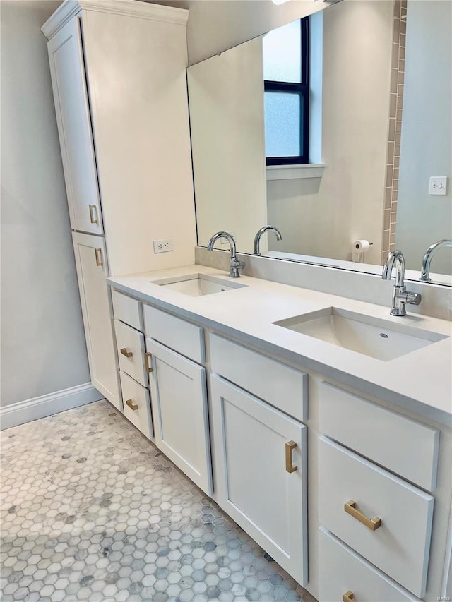 full bath with double vanity, tile patterned floors, a sink, and baseboards