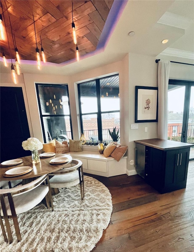 dining area with a healthy amount of sunlight, wood ceiling, a raised ceiling, and wood finished floors