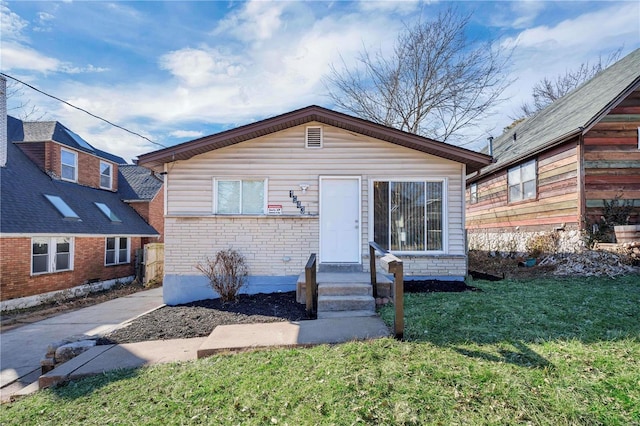 bungalow featuring brick siding and a front yard