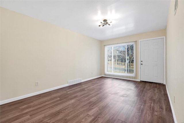 empty room featuring dark wood-style floors, baseboards, and visible vents