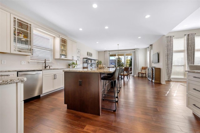 kitchen featuring dishwasher, dark wood-style floors, a center island, and a kitchen breakfast bar