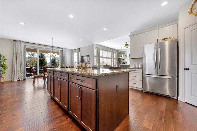 kitchen featuring dark wood-style floors, a center island, freestanding refrigerator, light stone countertops, and recessed lighting