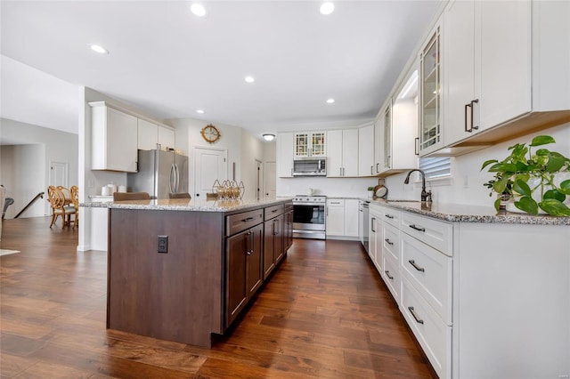 kitchen featuring glass insert cabinets, white cabinetry, stainless steel appliances, and a sink