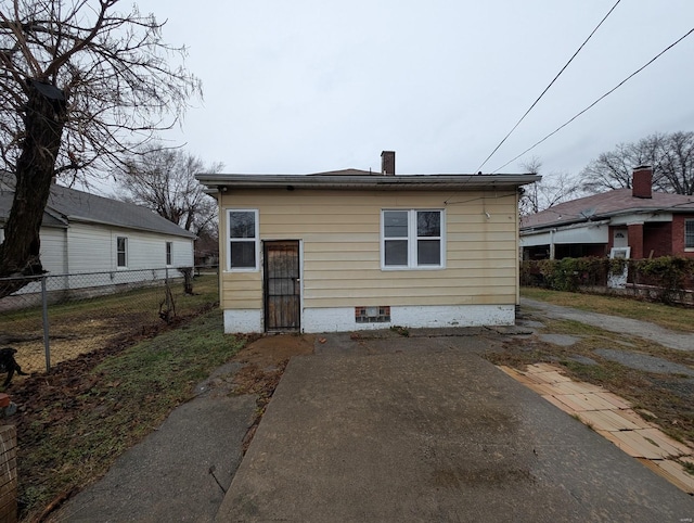 rear view of property featuring a patio, a chimney, and fence