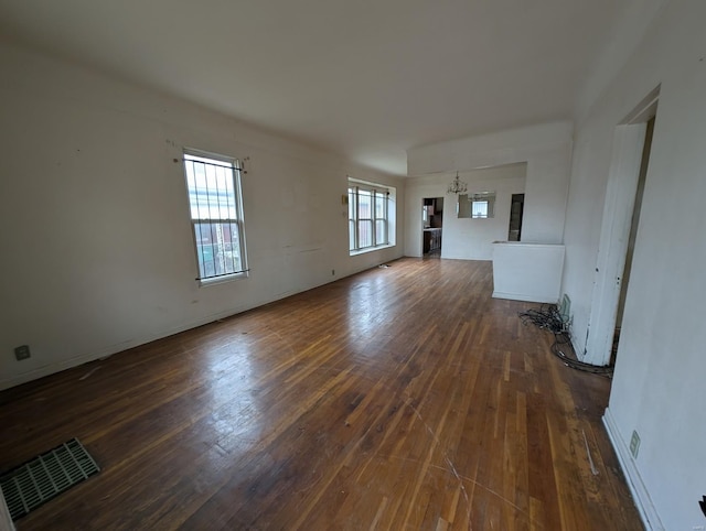 unfurnished living room featuring dark wood finished floors, visible vents, and an inviting chandelier