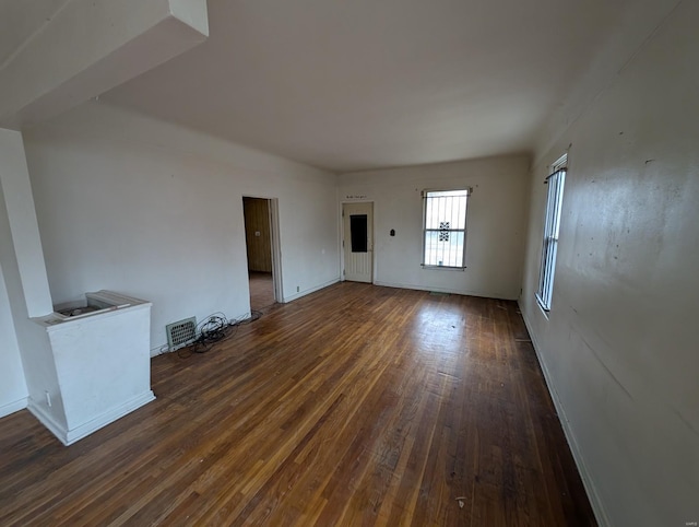 unfurnished living room with baseboards, visible vents, and dark wood-style flooring