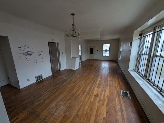 unfurnished dining area featuring baseboards, dark wood-style flooring, visible vents, and a notable chandelier