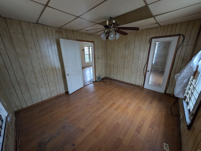 interior space featuring a paneled ceiling, wooden walls, and wood finished floors