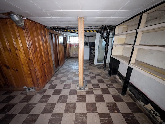 below grade area featuring wood walls, dark floors, and washer / dryer