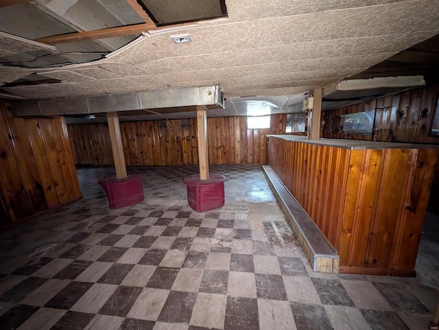 below grade area featuring wooden walls, a dry bar, and tile patterned floors