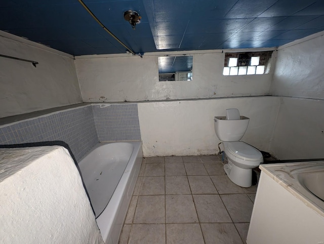 bathroom featuring a tub to relax in, tile patterned flooring, vanity, and toilet