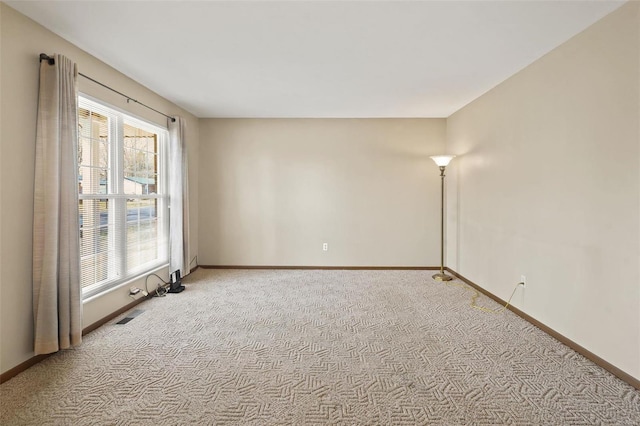 empty room featuring baseboards and light colored carpet