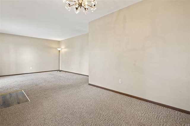 empty room featuring baseboards, carpet, and an inviting chandelier