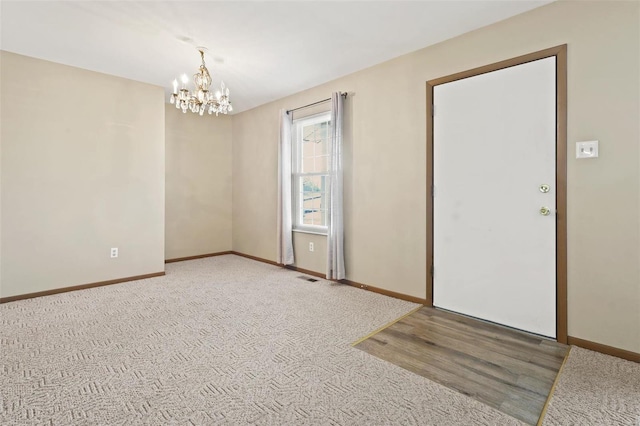 carpeted entrance foyer featuring visible vents, baseboards, and a chandelier