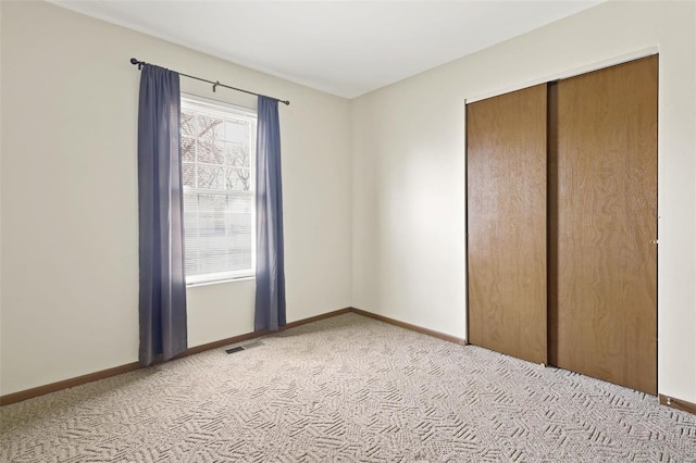 unfurnished bedroom with light carpet, visible vents, a closet, and baseboards