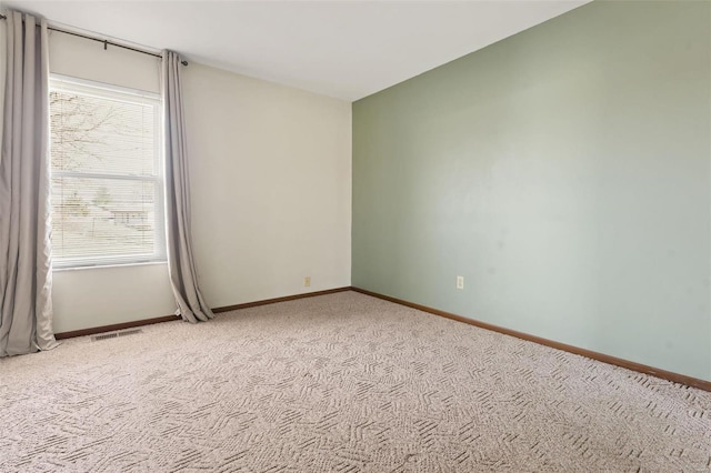 spare room with light colored carpet, visible vents, and baseboards