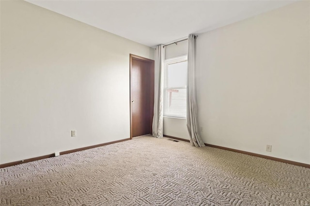 empty room with visible vents, baseboards, and light carpet