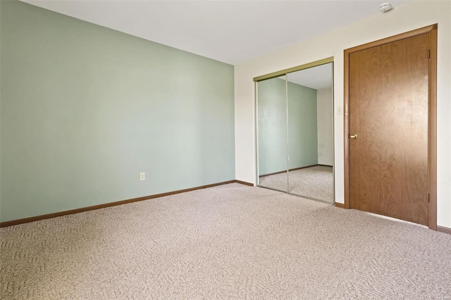 unfurnished bedroom with a closet, baseboards, and light colored carpet