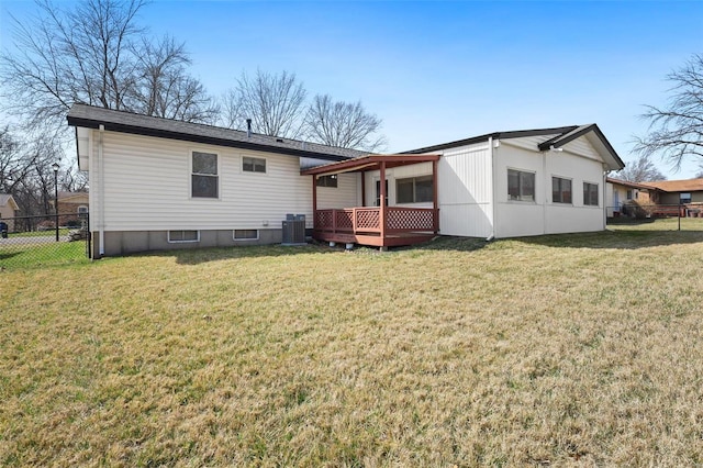 rear view of property with a wooden deck, a lawn, central AC, and fence