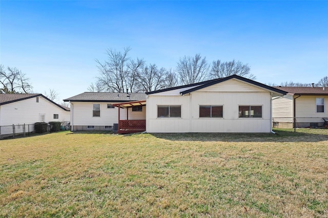 rear view of property featuring a lawn and fence