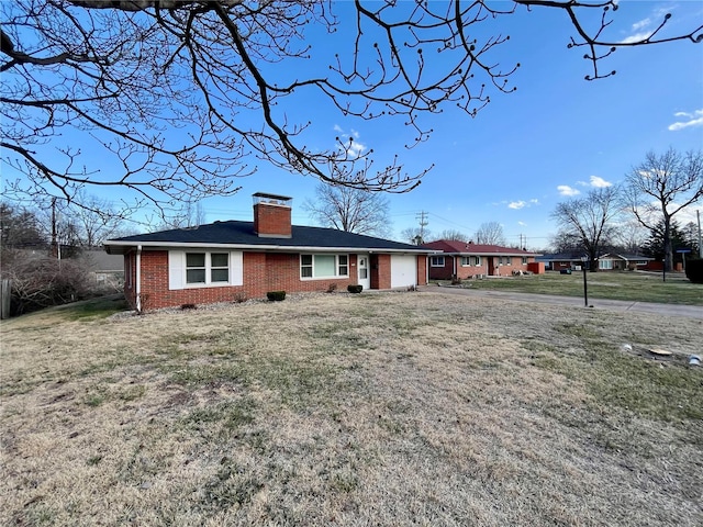 ranch-style home with brick siding, concrete driveway, a front yard, a chimney, and an attached garage