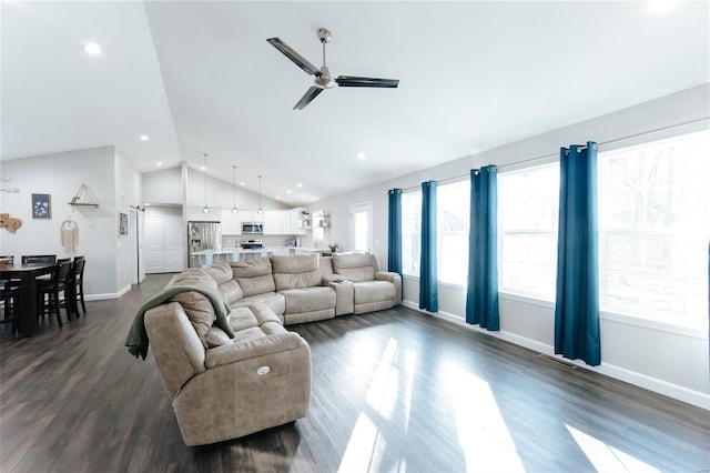 living room featuring lofted ceiling, ceiling fan, dark wood-type flooring, and a healthy amount of sunlight