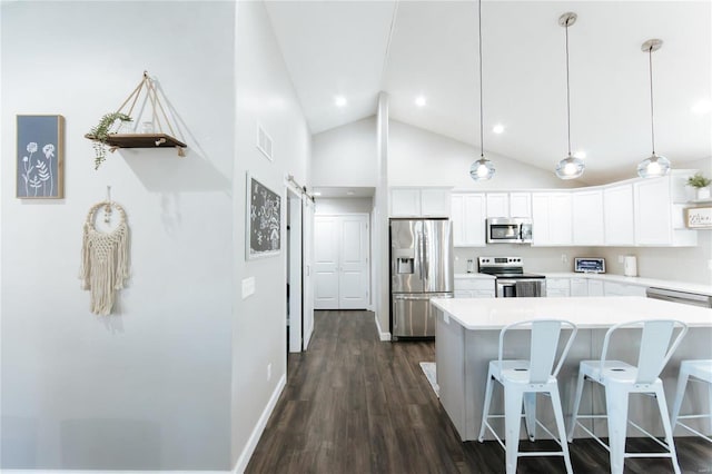 kitchen with dark wood finished floors, visible vents, a barn door, appliances with stainless steel finishes, and white cabinetry