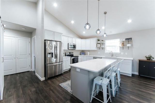 kitchen featuring a breakfast bar, open shelves, stainless steel appliances, dark wood-type flooring, and white cabinets