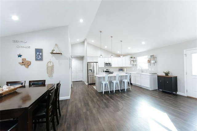 kitchen featuring white cabinetry, appliances with stainless steel finishes, a center island, open shelves, and a kitchen bar