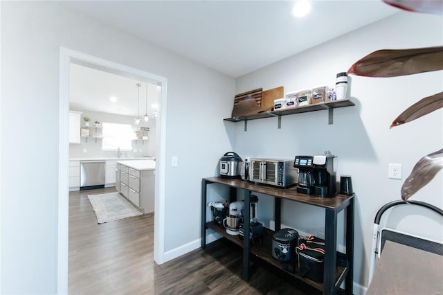 interior space with a sink, baseboards, stainless steel dishwasher, and wood finished floors