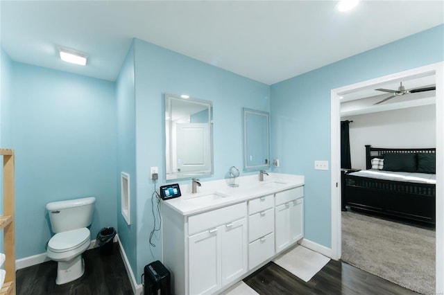 bathroom with double vanity, a sink, toilet, and wood finished floors