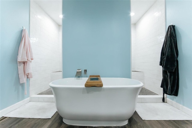 bathroom featuring a freestanding bath, walk in shower, and wood finished floors