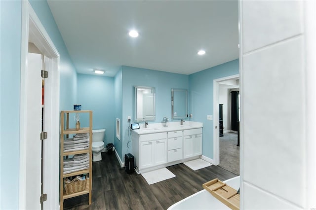 full bath with a sink, double vanity, wood finished floors, and toilet