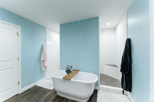 full bath featuring baseboards, wood finished floors, walk in shower, a freestanding bath, and recessed lighting